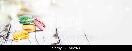 Banner mit Makronen. Biss fehlt von einer Zitrone französisch Macaron vor einem weißen rustikalen Tisch.. Selektiver Fokus mit verschwommenem Hintergrund und Kopie en Stockfoto