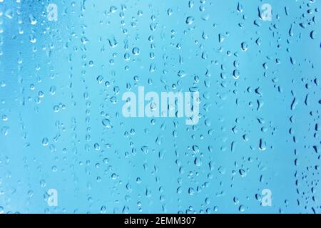 Wassertropfen Hintergrund. Wassertropfen auf Glasfenster über blauem Kontext Stockfoto