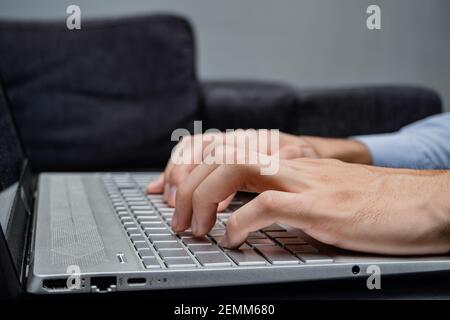 Ein Mann tippt auf seinem Laptop ganz grau und modern, trägt einen Anzug und eine intelligente Uhr, Labor Day. Stockfoto