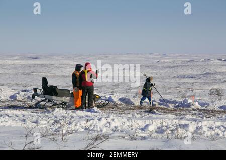 Vermesser bei der Arbeit an der gefrorenen Tundra während des Winterbaus des Inuvik-Tuktoyaktuk Highway, Northwest Territories, Kanadas Arktis. Stockfoto