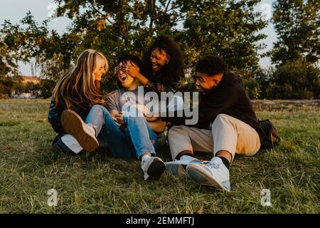 Junge männliche und weibliche Freunde spielen im Park während des Sonnenuntergangs Stockfoto