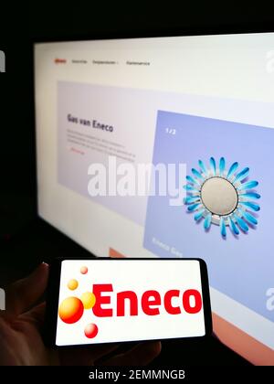 Person, die Mobiltelefon mit Firmenlogo des niederländischen Energieunternehmens Eneco Groep NV auf dem Bildschirm vor der Website hält. Konzentrieren Sie sich auf die Anzeige von Mobiltelefonen. Stockfoto
