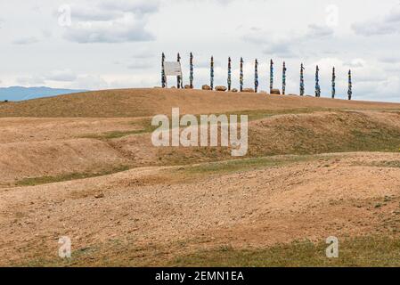 Eine Reihe von Sergen in Shamanka auf Olchon Island. Reihe von 13 hohen Ritual Buryat religiösen Säulen mit farbigen Bändern gebunden, vor dem Hintergrund blau Stockfoto