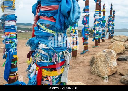 Close-up Reihe von hohen Ritual Buryat religiösen Säulen gebunden mit farbigen Bändern, vor dem Hintergrund blauen Himmel mit Wolken. Khuzhir ist die Hauptvilla Stockfoto