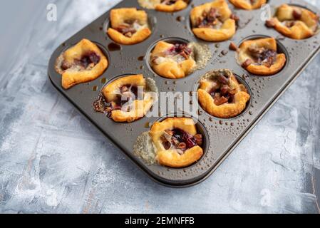 Brie beißt mit Marmelade und Nüssen in Halbmondteig, Mini-Vorspeise Dessert mit Preiselbeere oder Gelee Stockfoto