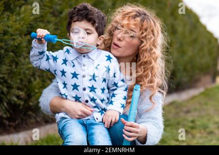 Mama spielt mit ihrem kleinen Jungen im Freien. Machen Seifenblasen mit Blasen kleben Stockfoto
