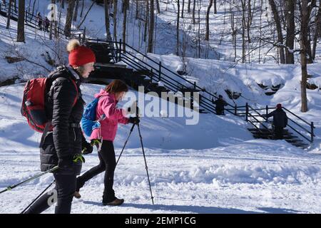 Montreal, CA - 2. Februar 2021: Zwei Frauen gehen nach einem Schneesturm auf einem verschneiten Trail im Mount Royal Park (Parc Du Mont-Royal) von Montreal. Stockfoto