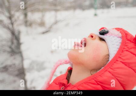 Kind fängt Schneeflocken auf der Zunge im Schneesturm Stockfoto