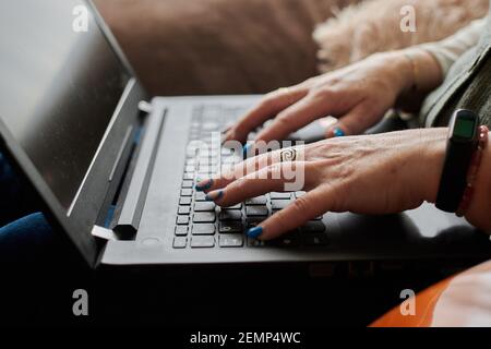 Nahaufnahme einer Frau mittleren Alters, die aus der Ferne mit ihrem Laptop arbeitet Stockfoto