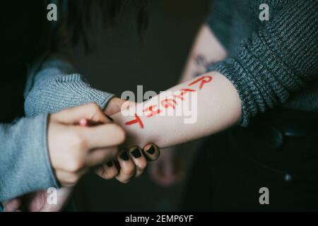 Zugeschnittenes Bild einer weiblichen Protesterin, die auf der Hand einer Frau schreibt Stockfoto