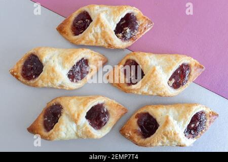 Auf zweifarbigem Hintergrund köstliches Blätterteig, gefüllt mit Himbeermarmelade. Draufsicht mit Kopierbereich. Nahaufnahme. Stockfoto