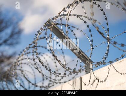Nahaufnahme scharfkantiger Stacheldraht-Stachelzaun, der sich aufwickelt Oben an der Gefängnismauer, die Gefangene und Kriminelle sicher hält Keine Verbindung Stockfoto