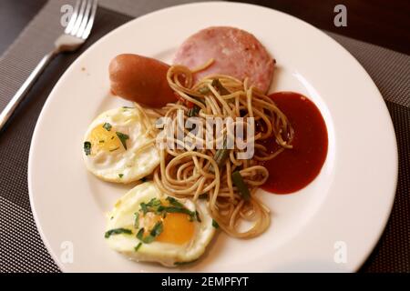 Spiegeleier mit Spaghetti und Speck auf dem Teller Stockfoto