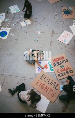 Direkt oberhalb von männlichen und weiblichen Protestierenden, die Plakate vorbereiten Soziale Probleme während der Pandemie Stockfoto