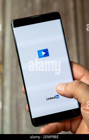 Ein Mobiltelefon oder Mobiltelefon, das von einem gehalten wird Hand mit der Linkedin-App auf dem Bildschirm geöffnet Stockfoto