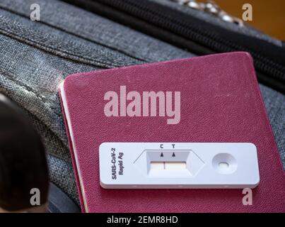 Pass und ein negatives covid-19 (Rapid Antigen SARS-CoV-2 AG ) Testergebnis auf dem Hintergrund des Gepäcks. Internationale Reisegenehmigung. Stockfoto