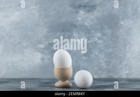 Eierbecher und Eier auf grauem Hintergrund Stockfoto