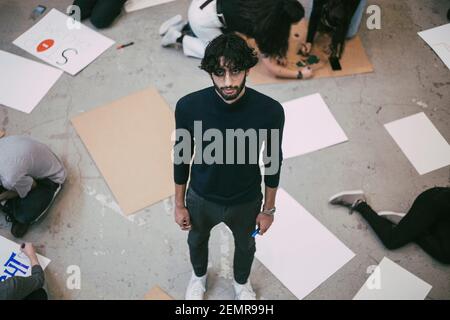 High-Angle-Ansicht des Mannes stehend, während männlich und weiblich Vorbereiten der Schilder im Gebäude Stockfoto