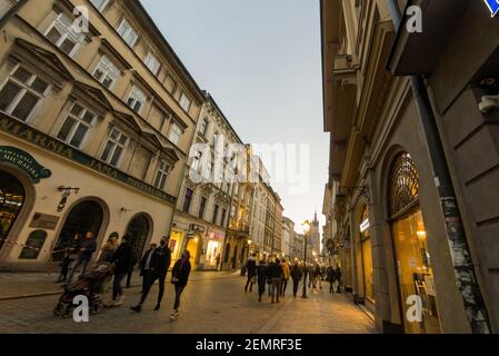 Krakau, Polen - 20. Februar 2021: Weitwinkelaufnahme einer europäischen Straße und Menschen, die abends in der Altstadt von krakau spazieren gehen. Peopl Stockfoto