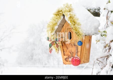 Vogelhaus mit Weihnachtsornamenten bei starkem Schneefall geschmückt; mit Kopierraum Stockfoto