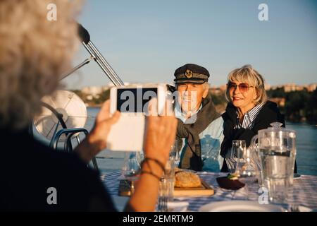 Zugeschnittenes Bild einer Frau, die ein älteres Paar im Boot fotografiert An sonnigen Tag Stockfoto