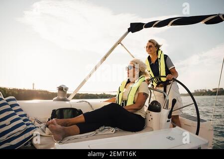 Fröhliche ältere Freundinnen im Boot an sonnigen Tag Stockfoto