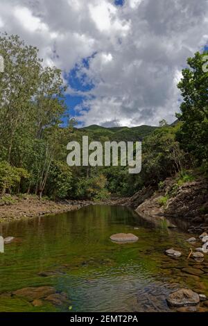 Der Black River, der durch die bergige Landschaft des Black River Gorge National Park in Mauritius führt, mit Wolken, die sich am blauen Himmel bilden. Stockfoto