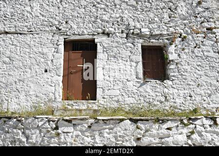 Traditionelle griechisch-orthodoxe Kapelle Fassade mit einer weiß getünchten Steinmauer und einem Kreuz auf der Holztür in Kastanitsa, Arcadia Peloponnes Griechenland. Stockfoto