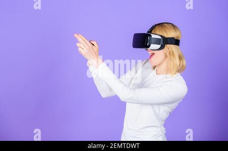 Virtual Reality-Drehgalerie. Mädchen verwenden moderne Technologie vr Headset spielen Shooter-Spiel. Dame mit Pistole Geste. Fesselnde Interaktion Virtual Reality. Frau Kopf montiert Display violetten Hintergrund. Stockfoto