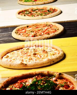 Verschiedene Pizzas auf der Speisekarte. Pizzakreise mit Fleisch, Pilzen, Tomaten und Käse auf Holzhintergrund. Italienische Pizza und Geschmackskonzept. Nehmen Sie Lebensmittel mit verschiedenen Zutaten und knackigen Kanten Stockfoto