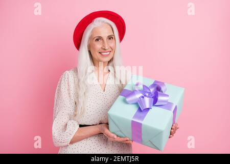 Portrait von attraktiven eleganten fröhlich grauhaarigen Oma in den Händen halten Romantisches Geschenk isoliert über rosa Pastellfarben Hintergrund Stockfoto