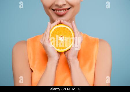 Beschnittene Ansicht der lächelnden Frau mit der Hälfte der reifen Orange Isoliert auf blau Stockfoto