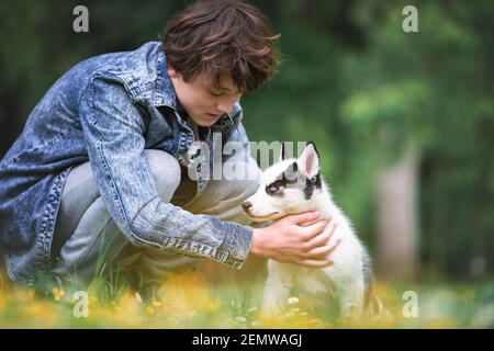 Teen mit weißen Hund Welpen züchten sibirischen Husky auf Frühling Hinterhof. Hunde und Haustiere Fotografie Stockfoto