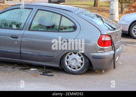 Das Detail eines verlassenen kaputten Autos, jetzt ein Wrack mit beschädigten oder gebrochenen Fenstern und voller Müll oder Abfall. Nimmt einen Parkplatz für den anderen Stockfoto