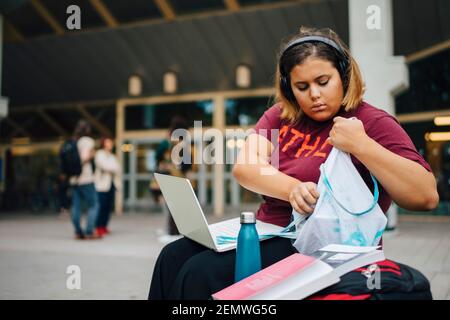 Weibliche College-Studentin guckt in Tasche, während sie in der Universität sitzt Stockfoto