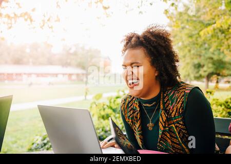 Studentin lacht beim Online-Studium über Laptop in der Hochschule campus Stockfoto