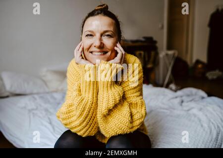 Porträt einer lächelnden Frau mit der Hand auf dem Kinn im Schlafzimmer Stockfoto