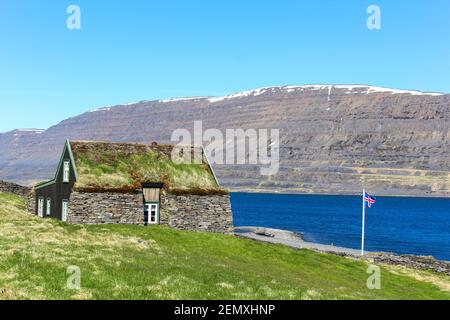 Isländische Flagge vor einem romantischen Rasenhaus, Island Stockfoto