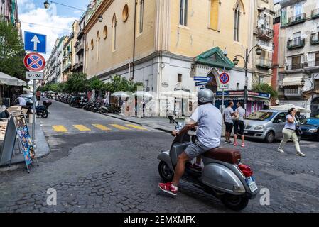 Neapel, Italien - 9. September 2019: Straße von alten Gebäuden mit einem Mann auf einer Vespa Motorrad in der Altstadt von Neapel, Italien Stockfoto