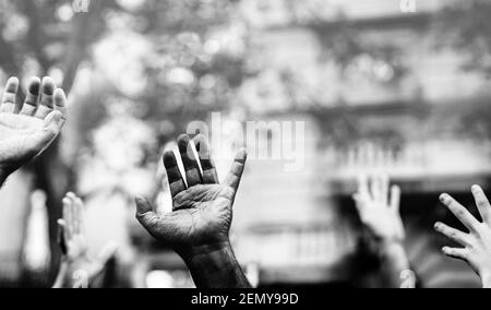 Offene Handfläche einer schwarzen Hand und weiße Hände in der Luft angehoben fordern Freiheit. Multikulturelle Hände bei einer Demonstration auf der Straße in schwarz-weiß. S Stockfoto