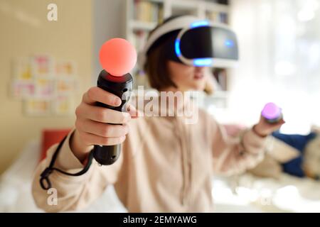 Hübsches Teenager-Mädchen trägt Virtual Reality-Headset zu Hause. Niedlicher Teenager mit VR-Brille ein Spiel zu spielen. Kind im virtuellen Augmented Reality Helm. Fut Stockfoto