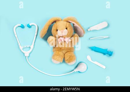 Ein Kaninchen heilen. Spielzeug Medizinprodukte auf blauem Hintergrund. Medizinische Instrumente für Kinder. Kinderarzt Konzept. Pädagogisches Spielzeug für Kinder Stockfoto