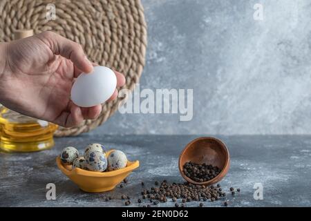Männliche Hand hält Hühnereier neben Wachteleiern Stockfoto