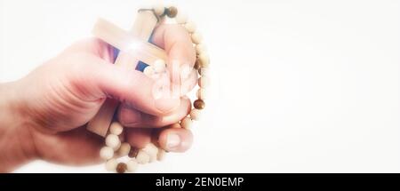 Hand hält mit Glauben ein Kreuz mit Holzperlen an Beten Sie mit Hoffnung mit isolierten weißen Hintergrund Stockfoto
