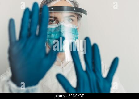 Gesundheitshelfer mit Schild und Maske mit Stop-Geste Stockfoto