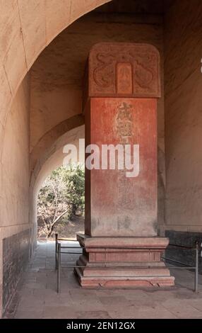 Peking, China - 28. April 2010: Ming-Gräber Changling. Nahaufnahme der stehenden roten Steinplatte, die Stele genannt wird, mit einer Nachricht in Mandarin unter dem Eingangstor. Stockfoto