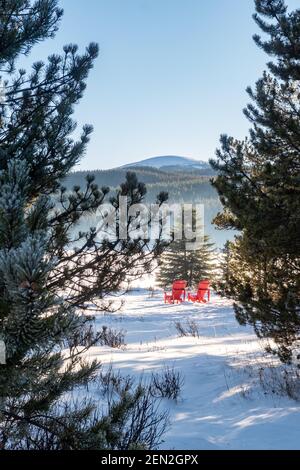 Winteransicht von zwei roten Adirondack-Stühlen am Maligne Lake im Jasper National Park, Kanada Stockfoto