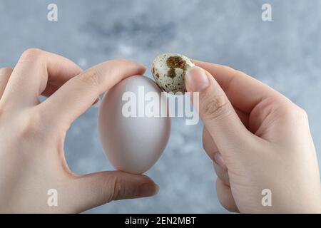 Weibliche Hand hält zwei Eier auf grauem Hintergrund Stockfoto