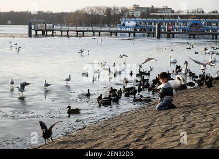 Berlin, Deutschland. Februar 2021, 25th. Ein Junge beobachtet Vögel am Tegeler See, bedeckt mit dünnem Eis in Berlin, Hauptstadt Deutschlands, 25. Februar 2021. Quelle: Shan Yuqi/Xinhua/Alamy Live News Stockfoto