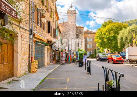 Eine Frau, die Geschäfte für Souvenirs und Postkarten auf einem Bürgersteig Geschäft außerhalb der mittelalterlichen Dorf Tourrettes-sur-Loup, Frankreich. Stockfoto